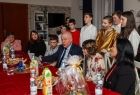 Wicemarszałek Ryszard Pagacz siedzi przy stole i śpiewa z dziećmi kolędy.