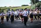 Strażacka orkiestra dęta w trakcie występu. W tle widoczna zieleń.