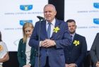 Wicemarszałek Ryszard Pagacz stoi przy mikrofonie. Za nim stoją inni ludzie.