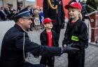 Wicemarszałek Łukasz Smółka klęczy przed małymi strażakami.
