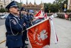 Policjanci stoją ze sztandarem.