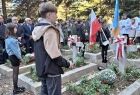 Ludzie stoją na cmentarzu wśród grobów.