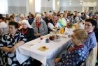 Uczestnicy jubileuszu zasiadający przy stołach ustawionych przed sceną