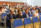 Publiczności siedzi na niebieskich fotelach.