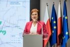 Radna Lidia Gądek stoi przy mównicy. Za nim widoczne flagi.