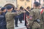 Uczniowie w mundurach ślubują przed sztandarem.