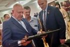 Wicemarszałek Ryszard Pagacz ogląda przedmiot na wystawie. Obok stoją inni ludzie.
