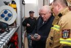 Wicemarszałek Ryszard Pagacz trzyma w rękach sprzęt strażacki. Obok stoi strażak.