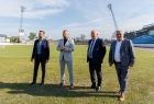 Wicemarszałek Ryszard Pagacz z innymi mężczyznami stoi na trawiastej płycie stadionu.