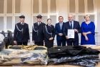 Wicemarszałek Ryszard Pagacz trzyma w rękach dyplom. Obok stoją inni ludzie.