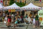 Ludzie stoją przed stoiskami ustawionymi na rynku.