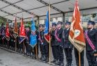 Strażacy stoją ze sztandarami.