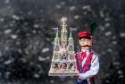 Postać krakowiaka trzyma szopkę krakowską.