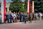 Ludzie stoją na runku. Z tyłu widoczne flagi.