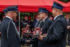 Strażacy trzymają w rękach modele wozów strażackich.