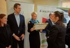 Prezes OSP Oświęcim wręcza Iwonie Gibas z zarządu województwa obraz przedstawiający wóz strażacki