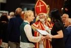 Iwona Gibas z zarządu województwa rozmawiająca z uczestnikami wydarzenia. Obok stoi przebrana postać ze złotym pastorałem, w czerwonym, haftowanym ornacie i biskupiej mitrze, przypominająca świętego Mikołaja
