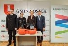 Iwona Gibas z Zarządu Województwa Małopolskiego, wójt Osieka Marek Jasiński oraz dwoje strażaków ochotników w galowych mundurach. Pamiątkowe zdjęcie z przekazanym sprzętem