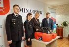 Iwona Gibas z Zarządu Województwa Małopolskiego, wójt Osieka Marek Jasiński oraz dwoje strażaków ochotników w galowych mundurach. Pamiątkowe zdjęcie z przekazanym sprzętem