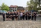 Wspólne pamiątkowe zdjęcie na rynku. Iwona Gibas z zarządu województwa oraz kilkudziesięcioosobowy zespół orkiestry dętej w Lanckoronie