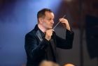 Dyrygent orkiestry z batutą w ręce rozpoczynający koncert w oświęcimskiej świątynki