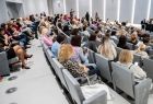 Uczestnicy wydarzenia zajmują miejsca na sali konferencyjnej