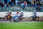 Żużlowcy jadą na motocyklach po torze.
