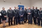 Wicemarszałek Ryszard Pagacz stoi ze strażakami na sali.