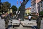 Żołnierze stoją na warcie przed pomnikiem z napisem Ofiarom Stalinizmu.