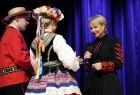 Przedstawiciele zespołu, para artystów w strojach ludowych, wręczają Iwonie Gibas z zarządu województwa okolicznościowy upominek 