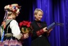 Przedstawiciele zespołu, para artystów w strojach ludowych, wręczają Iwonie Gibas z zarządu województwa okolicznościowy upominek 