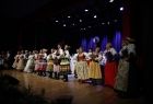Grupa artystów w strojach ludowych na scenie Domu Kultury w Wolbromiu