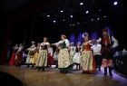 Grupa artystów w strojach ludowych podczas świąteczno-jubileuszowego koncertu na scenie Domu Kultury w Wolbromiu