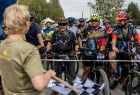 Iwona Gibas z zarządu województwa stojąca z flagą służącą do sygnalizacji startu przed czekającymi na ten sygnał uczestnikami rajdu rowerowego 