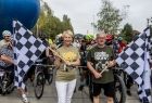 Iwona Gibas z zarządu województwa stojąca z flagą służącą do sygnalizacji startu przed czekającymi na ten sygnał uczestnikami rajdu rowerowego 