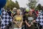 Iwona Gibas z zarządu województwa stojąca z flagą służącą do sygnalizacji startu przed czekającymi na ten sygnał uczestnikami rajdu rowerowego 