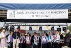 Grupa ludzi na scenie. U góry napis Saktuaryny Festyn Rodzinny w Tuchowie. 