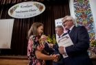 Wicemarszałek Józef Gawron wręcza dyplom dziewczynie w kwiecistej sukience.