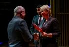 Iwona Gibas z zarządu województwa oraz marszałek Łukasz Smółka wręczający pracownikom okolicznościowe dyplomy i kwiaty