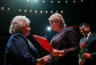 Iwona Gibas z zarządu województwa oraz marszałek województwa Łukasz Smółka wręczający długoletnim pracownikom Opery Krakowskiej pamiątkowe dyplomy oraz kwiaty