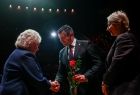 Marszałek Województwa Małopolskiego Łukasz Smółka oraz Iwona Gibas z zarządu województwa wręczający osobom współtworzącym przez lata Operę Krakowską pamiątkowe dyplomy oraz kwiaty