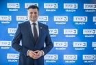 Marszałek Łukasz Smółka na tle ściany z logiem TVP3 Kraków. 
