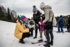 Marta Malec-Lech z zarządu województwa rozdaje dzieciom odblaski, które są w białym koszyczku.