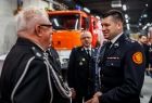 Marszałek Łukasz Smółka w galowym strażackim mundurze podczas rozmowy z doświadczonym strażakiem 