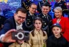 Poseł Łukasz Kmita wykonujący telefonem komórkowym pamiątkowe zdjęcia z udziałem strażackiej młodzieży oraz marszałka Łukasza Smółki i Iwony Gibas z zarządu województwa