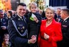 Marszałek Łukasz Smółka w galowym strażackim mundurze trzymający na ręku małą dziewczynkę. Tuż obok Iwona Gibas z Zarządu Województwa Małopolskiego