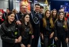 Marszałek Łukasz Smółka w galowym mundurze otoczony członkiniami młodzieżowej drużyny pożarniczej