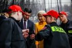 Wicemarszałek Łukasz Smółka i Iwona Gibas z zarządu województwa otoczeni wkoło strażacką młodzieżą, oglądający współnie emblemat, element strażackiego ekwipunku