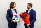 Mężczyzna w garniturze wręcza bukiet róż Marcie Malec-Lech z zarządu. 