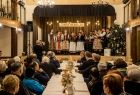 Uczestnicy spotkania świątecznego siedzą przy stole